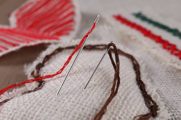 A young woman wearing a white shirt is engaged in a craft activity, carefully handling pink fabric with her hands, focusing on a detailed task related to sewing or fabric manipulation in an indoor setting with soft light coming through a window