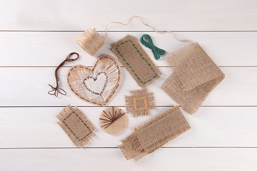 Flat lay composition with pieces of burlap fabric on white wooden table
