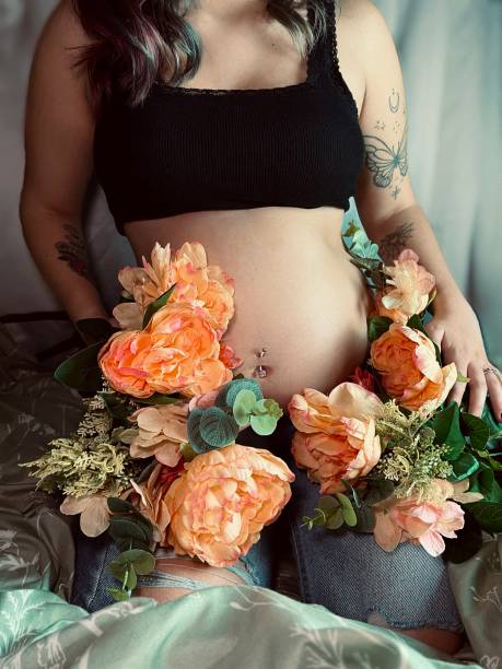 retrato mal-humorado de uma mulher adulta jovem grávida com flores. - pierced abdomen flower beauty - fotografias e filmes do acervo