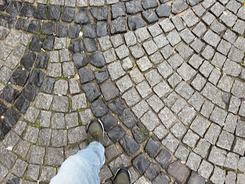 Point of view of feet on a cobblestone street. Walking away.