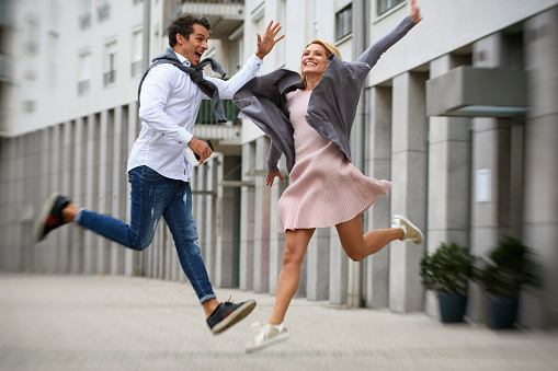 Man and woman jumping in city. City life lifestyle.