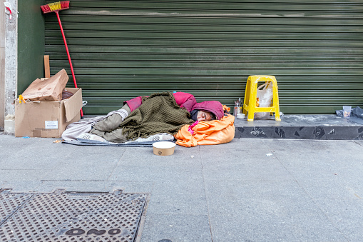Seville, Spain - December 20, 2023: An old person sleeps on the street in Seville