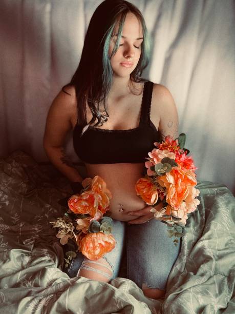 retrato mal-humorado de uma mulher adulta jovem grávida. - pierced abdomen flower beauty - fotografias e filmes do acervo