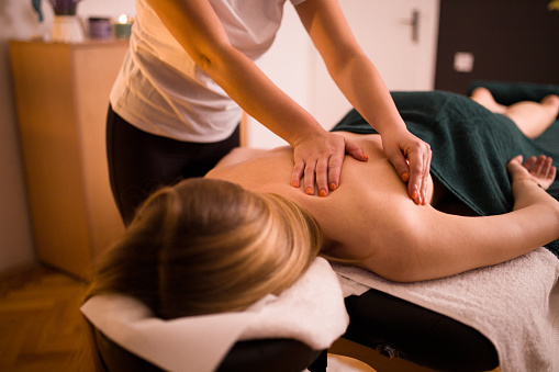 Back massage, young blonde woman enjoying  massage at beauty spa salon