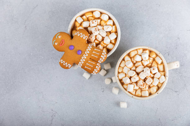 Hot drink with marshmallows and candy cane in cup on texture table.Cozy seasonal holidays.Hot cocoa with gingerbread Christmas cookies.Hot chocolate with marshmallow and spices.Copy space.