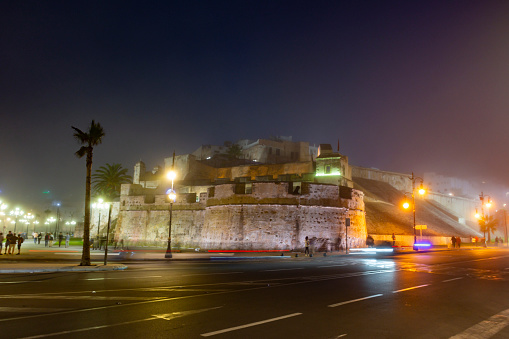 Tangier, Morocco. October 15th, 2022 - Night image of the Dar El-Barudla Tower on the medina wall, next to the port, with fog, at the kilometer 0 point of entry to Africa