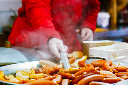 Cook cooking sausages for hot dogs in a large frying pan