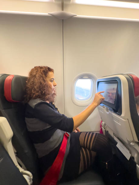 istock Young woman in airplane using onboard entertainment 1925563424
