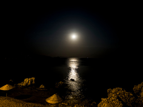 Moon rising over the Red Sea just before sunset. Two local fising boats moored close to the beach.