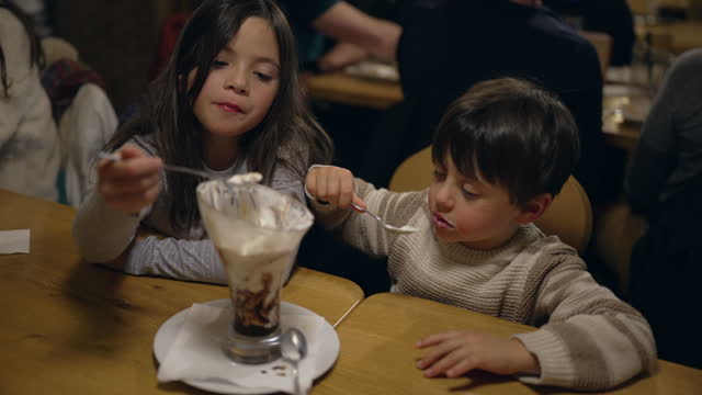 Youthful Joy in Sweet Treat - Young Brother and Sister Savoring Whipped Cream Sundae at Local Diner on Weekend Night