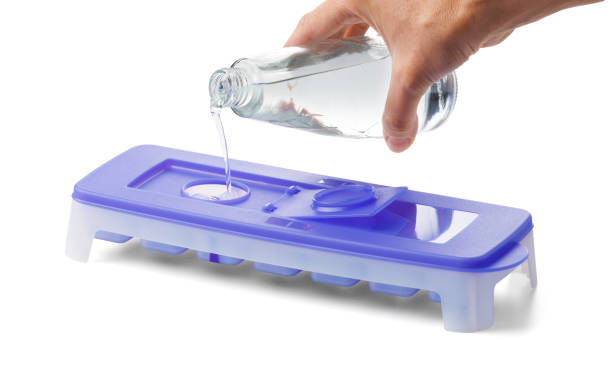 istock Water pours into a mold for ice cubes on a white background, closeup. 1925580312