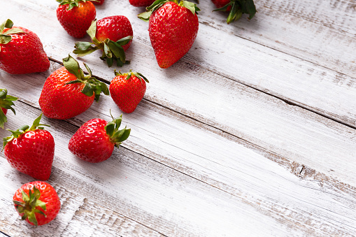 Berries of large ripe fresh organic strawberries on a wooden background with space for text.