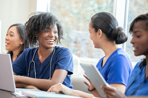 Happy young nursing student discusses medical class assignment with other healthcare workers