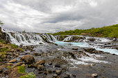 The blue water of the Bruarfoss waterfall flows down in cascades.