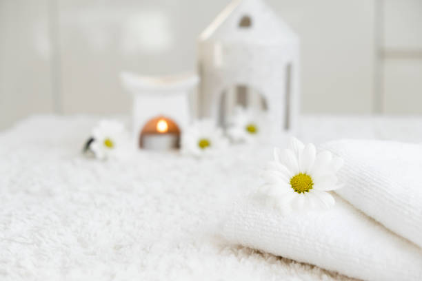 White towels with chamomile flower and aroma lamp, candle. Spa and wellness or beauty salon, romantic relaxation concept. Copy space. Womens Day. Valentines Day.