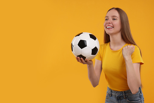 Happy sports fan with ball on yellow background. Space for text