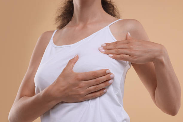 istock Woman doing breast self-examination on light brown background, closeup 1925635582
