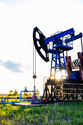 An active oil rig operating at sunrise or sunset. Resource extraction, oil crisis