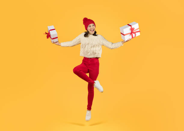 istock lady in knitwear holds two presents boxes on yellow background 1925646077