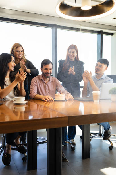 istock Man blowing candles from a birthday cake he just got from his coworkers 1925649332