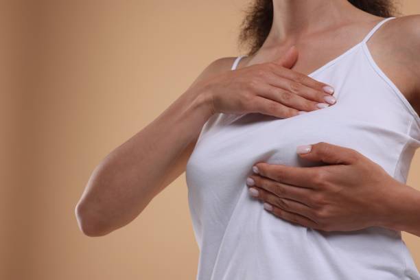istock Woman doing breast self-examination on light brown background, closeup. Space for text 1925661900