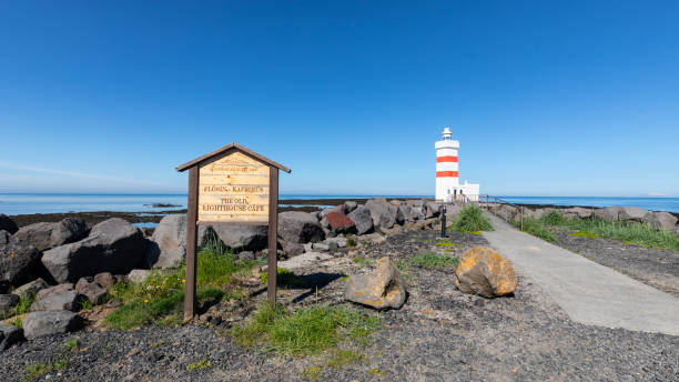 istock White, red, striped lighthouse off the coast of Iceland. 1925666151