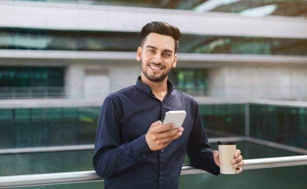 istock Arab entrepreneur man with smartphone and coffee paper cup outside 1925672048