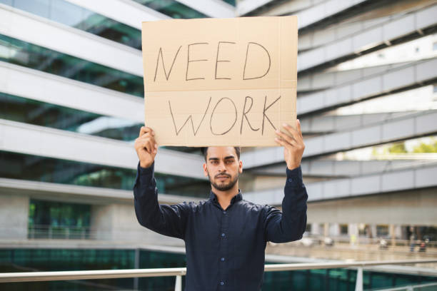 istock Unhappy middle eastern businessman holding Need Work paper poster outside 1925672056