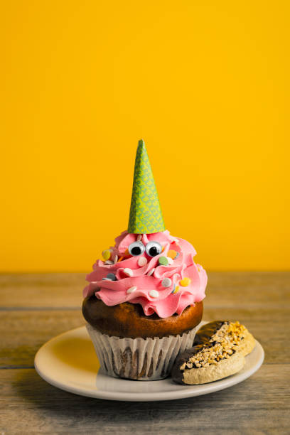istock Cookies and Cute Cupcake With Eyes and Prty Hat on Yellow 1925706773