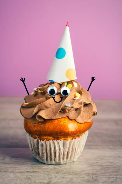 istock Cute Chocolate Cupcake Character in Party Hat With Hands in the Air 1925707306