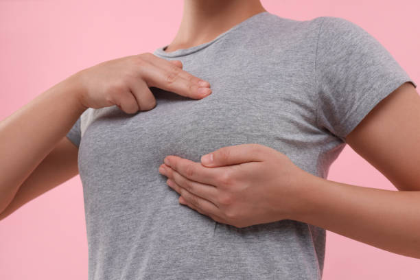 istock Woman doing breast self-examination on pink background, closeup 1925716313