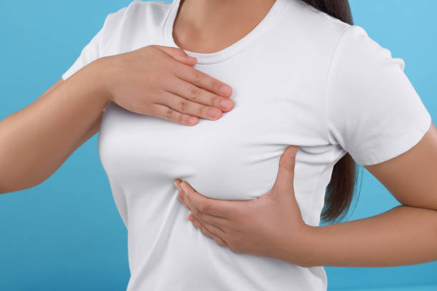 istock Woman doing breast self-examination on light blue background, closeup 1925721120
