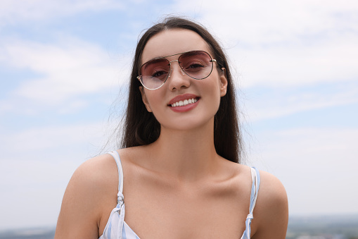 Beautiful smiling woman wearing stylish sunglasses outdoors