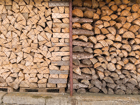 Large firewood wood pile made up of many small, neatly stacked brown pieces of wood