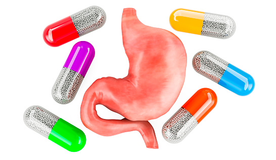 Human stomach with medicine capsules around, 3D rendering isolated on white background