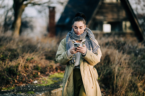 Young woman taking a selfie and using a smartphone on a lovely winter day in nature