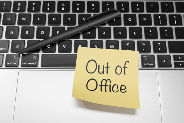 istock Yellow sticky note written with the message Out of Office stuck on a silver laptop. Illustration of the concept of annual leave and public holidays of employees 1925797259