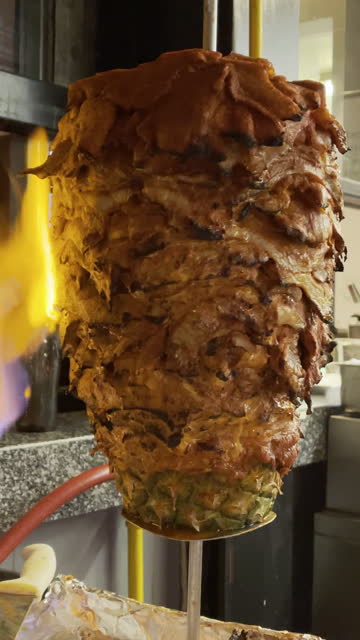 Tacos Al Pastor Pork and Beef Meat Being Sliced from a Rotisserie Spit in an Open Air Restaurant in Downtown Mazatlan Mexico