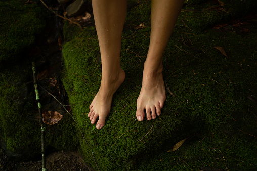 Bare feet set upon a green mossy stone