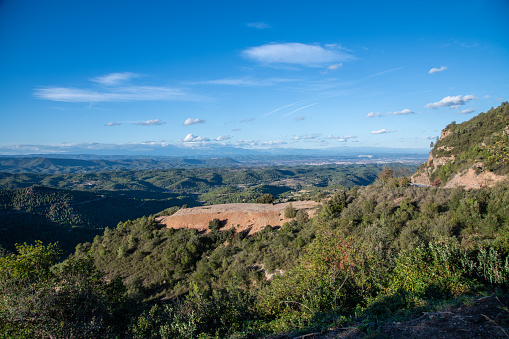 View over the mountains of Montserrat. When the sky is blue, you can see a plateau that lies in the middle of forests.