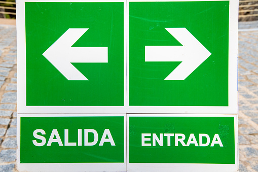 A collection of signs in the Spanish language. On the left side, there are two signs, one with an arrow and the other with the word 