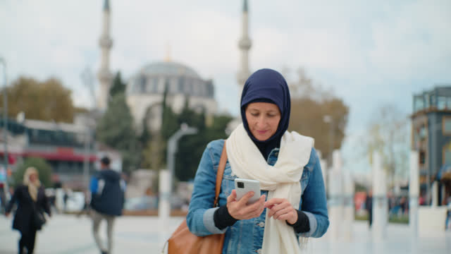 WS Female Tourist Uses her Smartphone while walking in front of a Mosque in Istanbul #MosqueConnection #DigitalContemplation #IslamicReflection