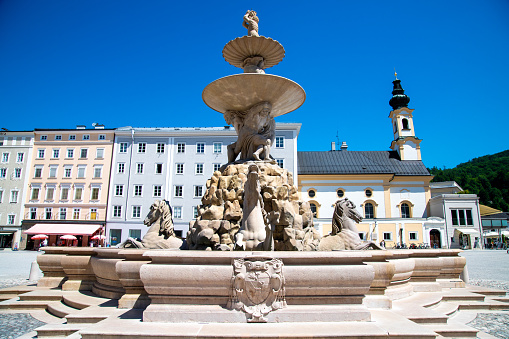 The residence fountain in Salburg made of stone. The fountain is made of smooth stone on the outside and rough stone on the inside. Four horses are arranged around the fountain.