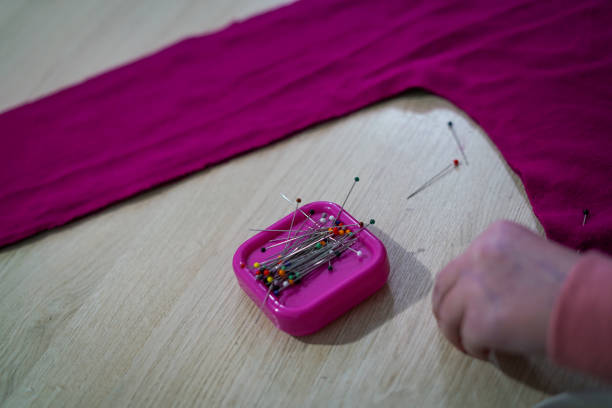 Close-up of the pins on a pincushion. The heads of the needles have different colours, the background is blurred.