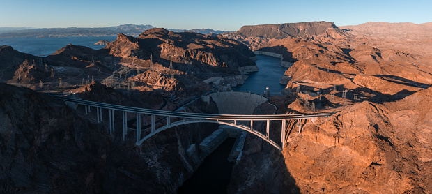 Hoover Dam on the Colorado River straddling Nevada and Arizona at dawn from above. Aerial view of Hoover Dam and the Colorado River Bridge