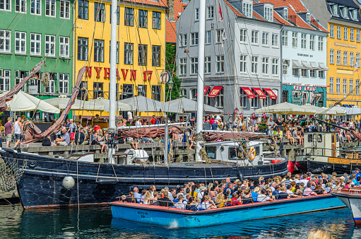 Copenhagen, Denmark - July 8, 2014: View of colorful houses, bars, restaurants and tourists in Nyhavn, a 17th-century waterfront, canal and entertainment district in Copenhagen, Denmark