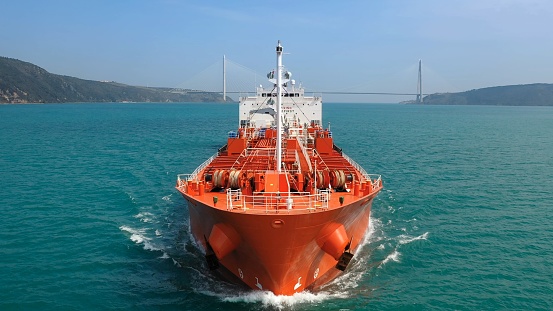 A supertanker loaded with crude oil sails towards the camera at full speed in the Bosphorus Sea. Red prow, bow, front deck, pipe lines and winches of oil products tanker underways ocean. Aerial Drone