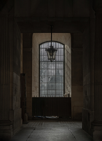 France, Paris - Jan 03, 2024 - Sunshine Through arched window alcove and lamp to The Louvre courtyards. Light and Shadow, Space for text, Selective focus.