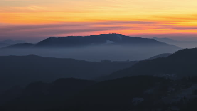 AERIAL Drone Shot of Beautiful Foggy Mountains Under Orange Sky during Golden Hour in Rogla, Slovenia