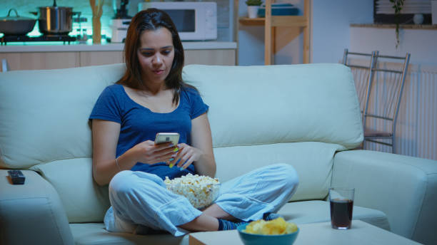 istock Woman scrolling on phone eating popcorn 1926023090